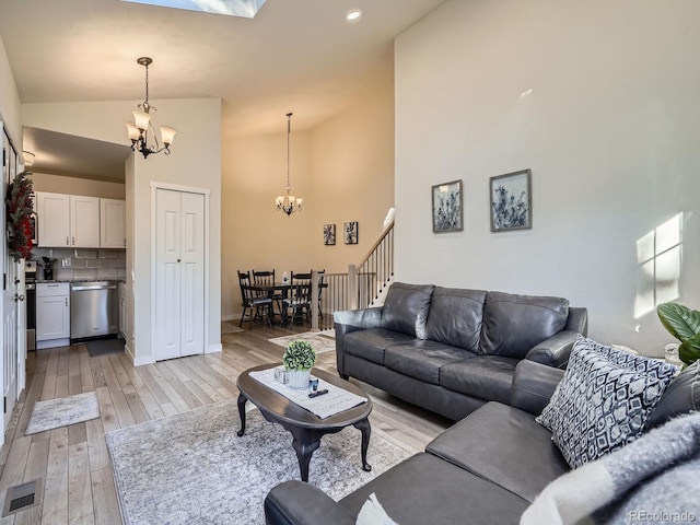 living room with light hardwood / wood-style floors, high vaulted ceiling, and an inviting chandelier