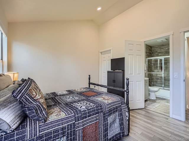 bedroom with connected bathroom, hardwood / wood-style floors, and vaulted ceiling