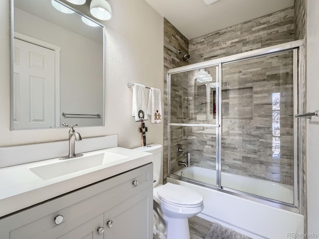 full bathroom with hardwood / wood-style floors, vanity, toilet, and bath / shower combo with glass door