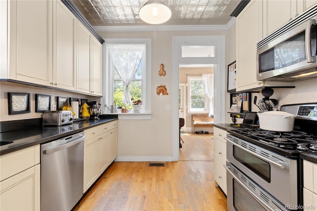 256 Bannock St, Denver, CO 80223 - kitchen with stainless steel appliances, an ornate ceiling, dark countertops, light wood-style floors, and crown molding