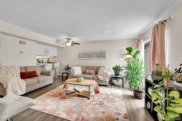 living room featuring ceiling fan, wood-type flooring, and a textured ceiling