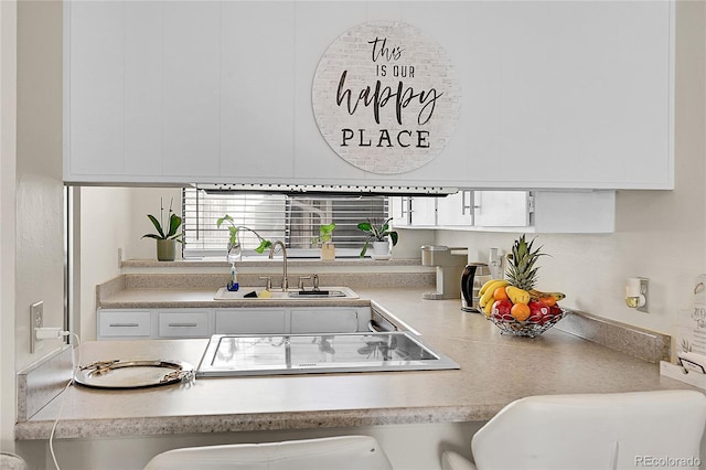 kitchen featuring stovetop, white cabinetry, and sink