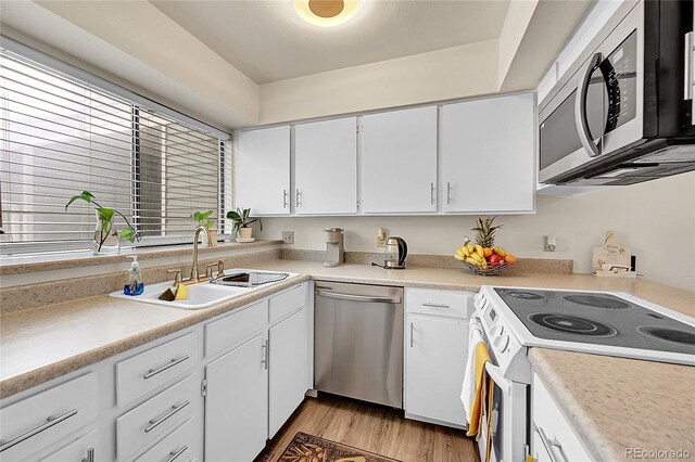 kitchen with sink, white cabinets, light hardwood / wood-style floors, and appliances with stainless steel finishes