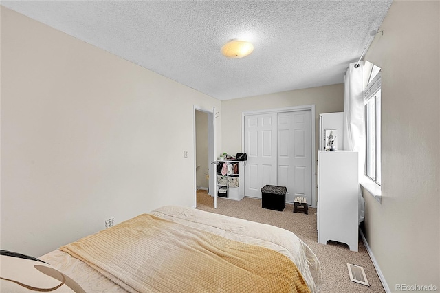 bedroom with a textured ceiling, carpet floors, and a closet