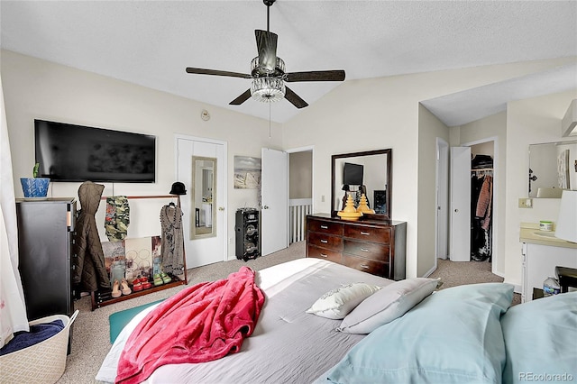 carpeted bedroom with a walk in closet, vaulted ceiling, ceiling fan, a textured ceiling, and a closet