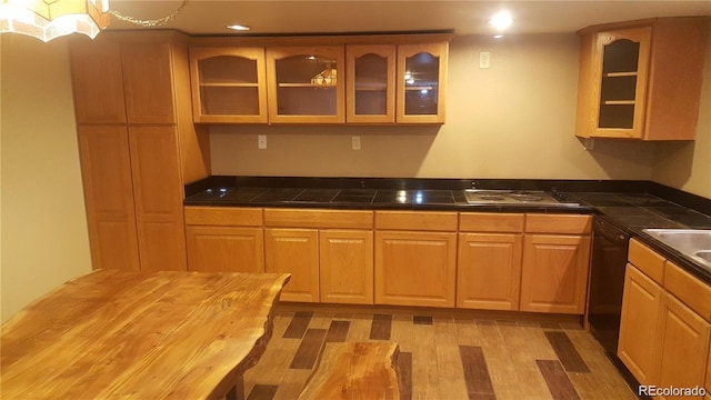 kitchen featuring cooktop, black dishwasher, and light hardwood / wood-style flooring