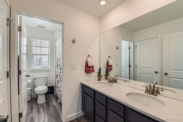 14551 Hudson St, Thornton, CO 80602 - bathroom featuring wood finished floors, toilet, double vanity, recessed lighting, and baseboards