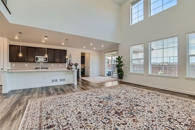 14551 Hudson St, Thornton, CO 80602 - kitchen featuring stainless steel microwave, wood finished floors, dark brown cabinets, light countertops, and healthy amount of natural light