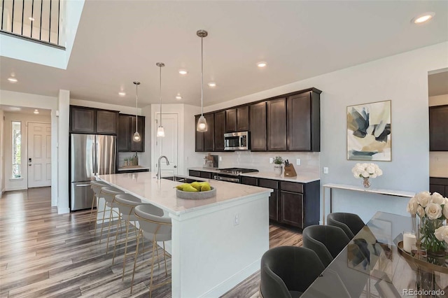 14551 Hudson St, Thornton, CO 80602 - kitchen with appliances with stainless steel finishes, dark brown cabinetry, a kitchen breakfast bar, wood finished floors, and light countertops