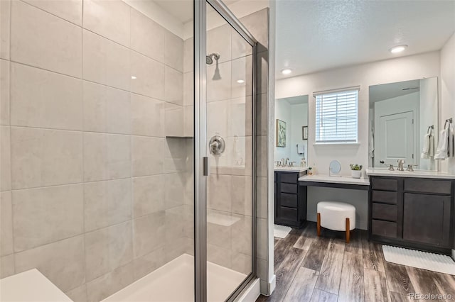 14551 Hudson St, Thornton, CO 80602 - bathroom featuring a shower stall, wood finished floors, and two vanities