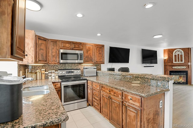 14396 E Temple Pl Unit D, Aurora, CO 80015 - kitchen with stainless steel appliances, a peninsula, a sink, open floor plan, and stone counters