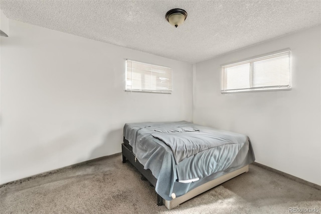 carpeted bedroom with multiple windows and a textured ceiling