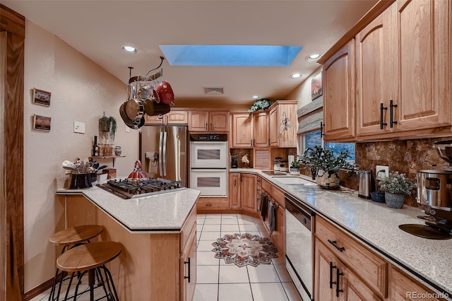 5900 W 62nd Ave, Arvada, CO 80003 - kitchen featuring stainless steel appliances, a skylight, a breakfast bar area, backsplash, and recessed lighting