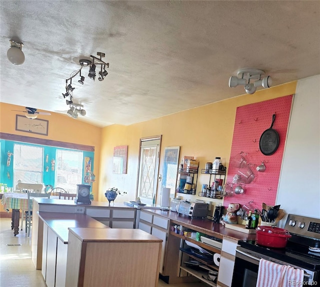 kitchen featuring ceiling fan, a textured ceiling, and stainless steel electric range oven