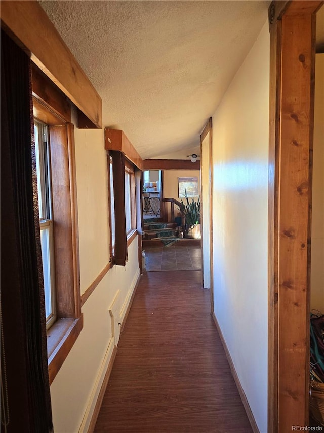 corridor featuring dark wood-type flooring, lofted ceiling, and a textured ceiling