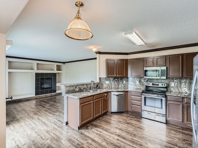5553 Jasper St, Denver, CO 80239 - kitchen with stainless steel appliances, a peninsula, ornamental molding, light wood finished floors, and open floor plan