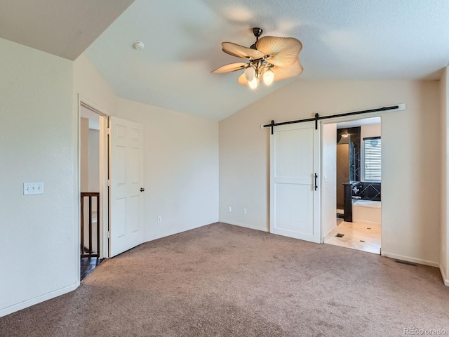 5553 Jasper St, Denver, CO 80239 - unfurnished bedroom with a barn door, carpet flooring, vaulted ceiling, ensuite bathroom, and ceiling fan