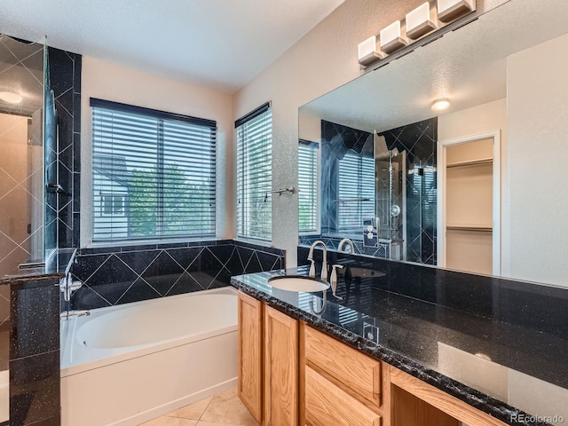 5553 Jasper St, Denver, CO 80239 - full bathroom with a bath, vanity, a stall shower, a spacious closet, and tile patterned floors
