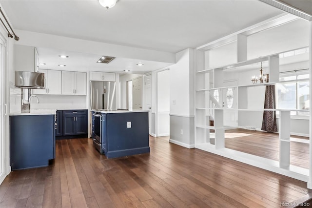 kitchen with blue cabinetry, a center island, dark hardwood / wood-style floors, and a notable chandelier