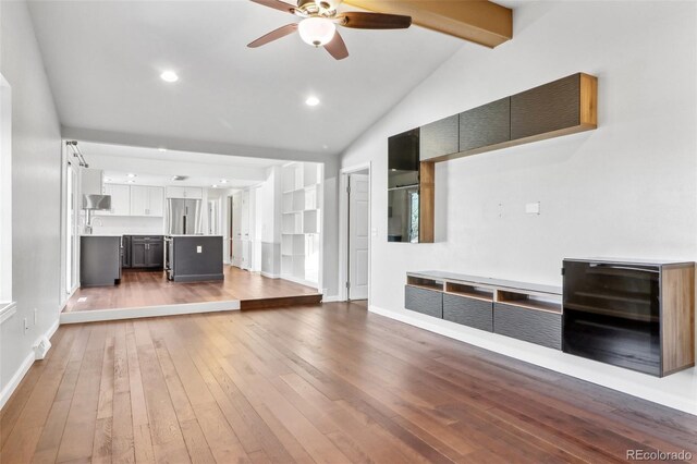 unfurnished living room featuring vaulted ceiling with beams, hardwood / wood-style flooring, ceiling fan, and sink