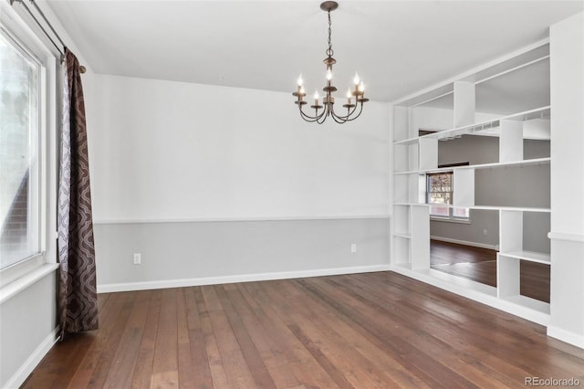 unfurnished room featuring plenty of natural light, wood-type flooring, and a chandelier