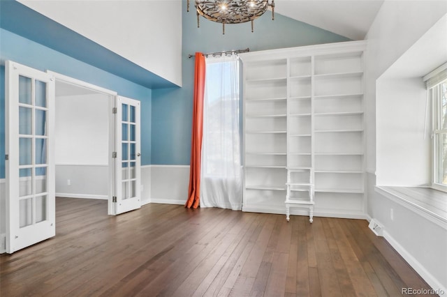 empty room with a chandelier, french doors, dark wood-type flooring, and lofted ceiling