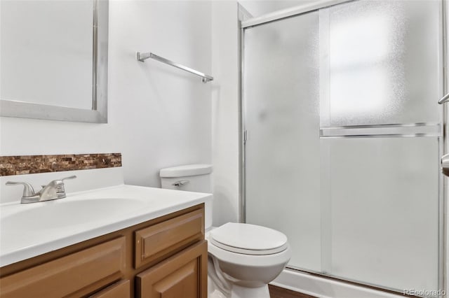 bathroom featuring vanity, a shower with shower door, and toilet