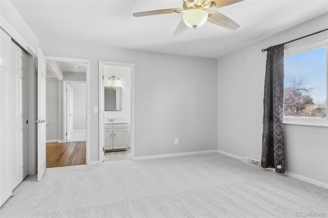 unfurnished bedroom featuring light carpet, a closet, ceiling fan, and ensuite bathroom