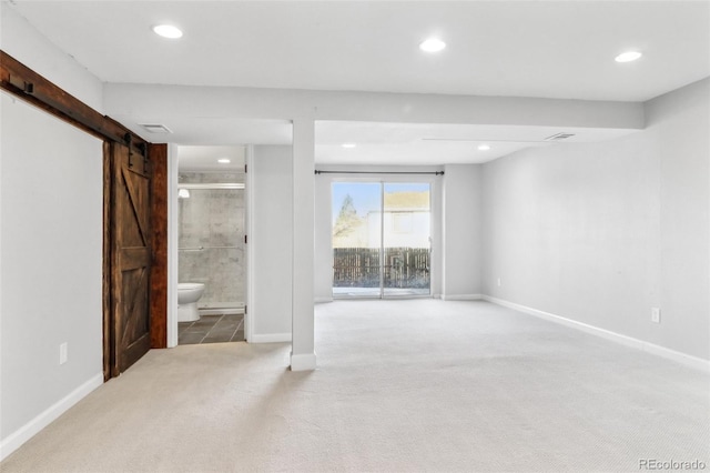 basement with a barn door and light colored carpet