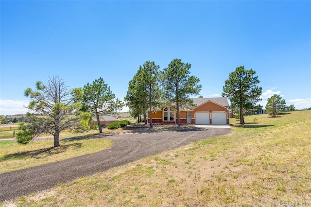 ranch-style home featuring a garage, a front lawn, and a rural view