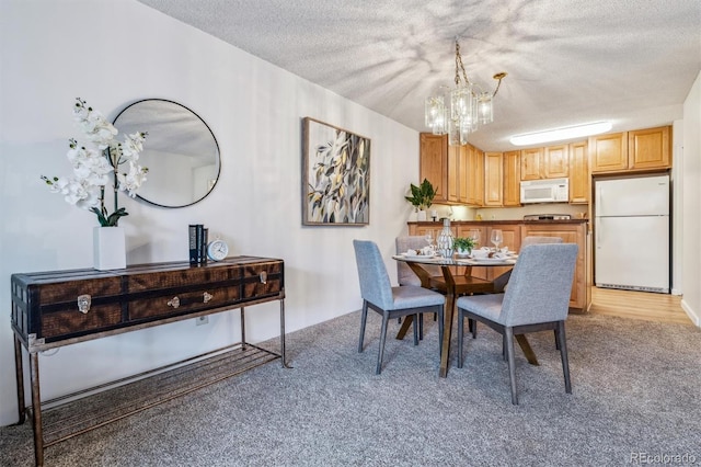 dining room featuring a textured ceiling, light carpet, and a chandelier