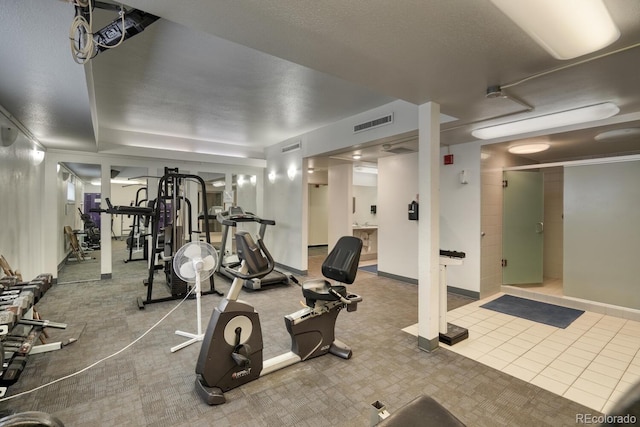 exercise room with tile patterned floors and a textured ceiling