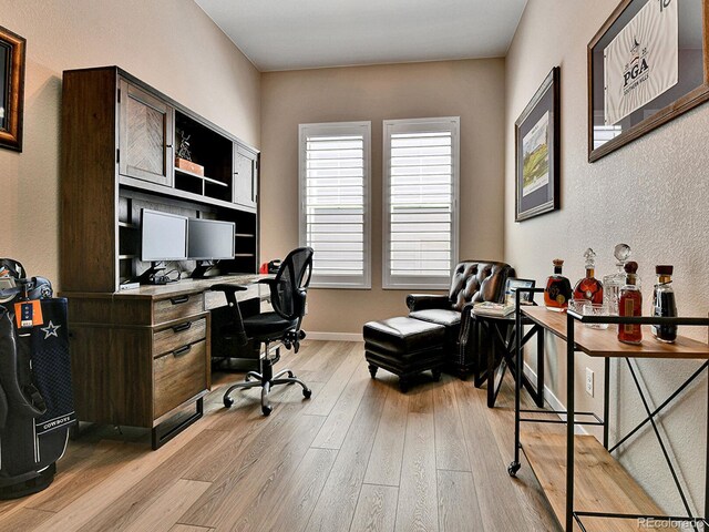 11464 Stonewash St, Littleton, CO 80125 - home office with light wood-type flooring, a textured wall, and baseboards