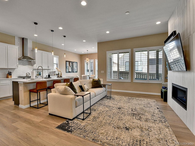 11464 Stonewash St, Littleton, CO 80125 - living area with light wood finished floors, recessed lighting, a glass covered fireplace, a chandelier, and baseboards