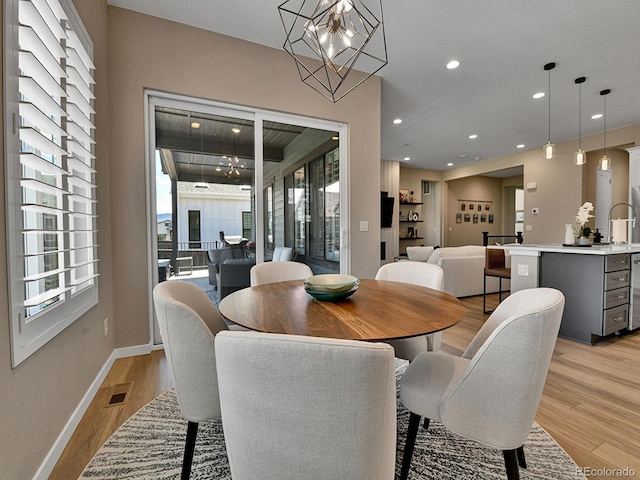 11464 Stonewash St, Littleton, CO 80125 - dining space with light wood finished floors, healthy amount of natural light, recessed lighting, a chandelier, and baseboards
