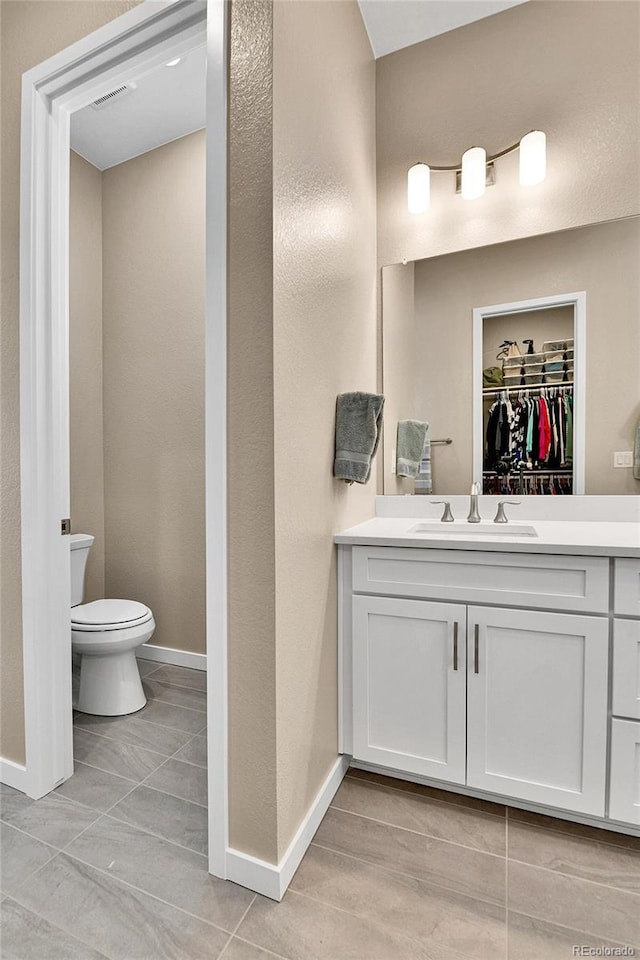 11464 Stonewash St, Littleton, CO 80125 - full bathroom with baseboards, vanity, toilet, and a spacious closet