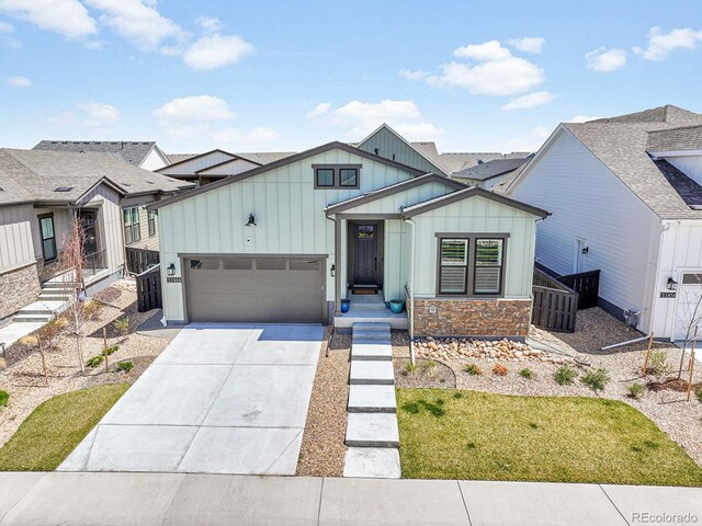 11464 Stonewash St, Littleton, CO 80125 - view of front of house featuring board and batten siding, a garage, driveway, fence, and stone siding