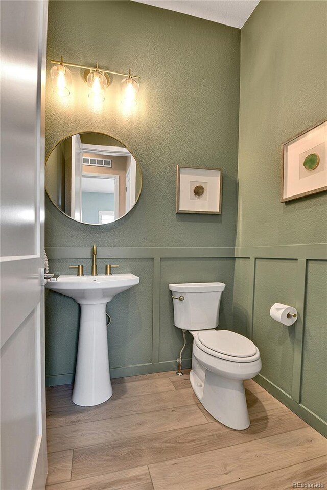 11464 Stonewash St, Littleton, CO 80125 - half bathroom with wood finished floors, toilet, a sink, and a decorative wall