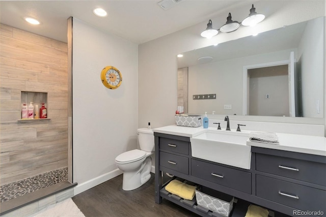 bathroom with vanity, tiled shower, hardwood / wood-style floors, and toilet