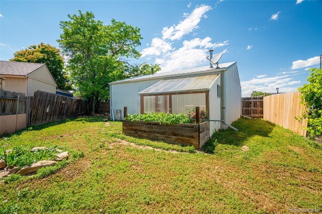 916 Glen Heather Ct, Dacono, CO 80514 - rear view of house with a vegetable garden, a fenced backyard, and a metal roof
