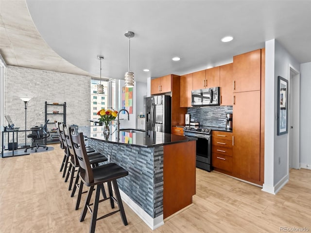 891 14th St Unit 1709, Denver, CO 80202 - kitchen featuring stainless steel appliances, dark countertops, a kitchen bar, light wood-type flooring, and backsplash