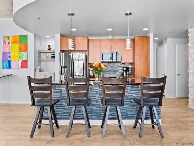 891 14th St Unit 1709, Denver, CO 80202 - kitchen featuring appliances with stainless steel finishes, light wood-type flooring, pendant lighting, a kitchen bar, and recessed lighting