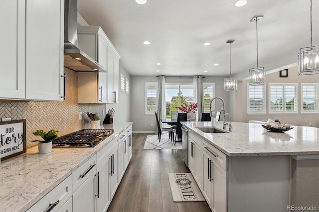 kitchen with dark wood-type flooring, a sink, backsplash, appliances with stainless steel finishes, and wall chimney range hood