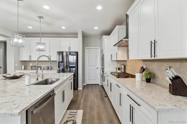 kitchen with a sink, wood finished floors, white cabinetry, stainless steel appliances, and wall chimney exhaust hood