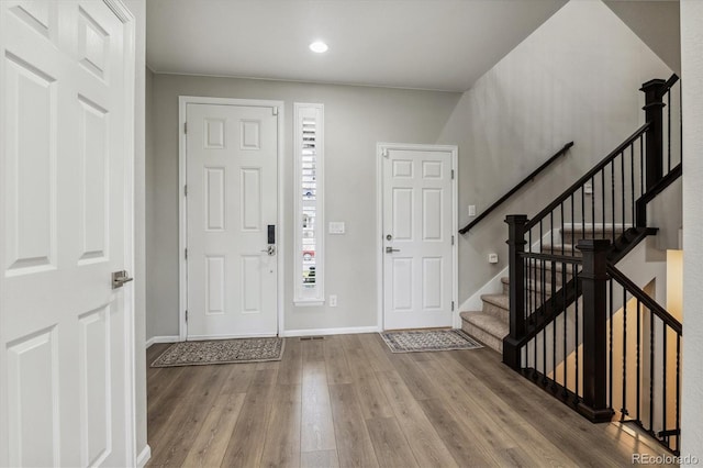 foyer with stairway, baseboards, and wood finished floors