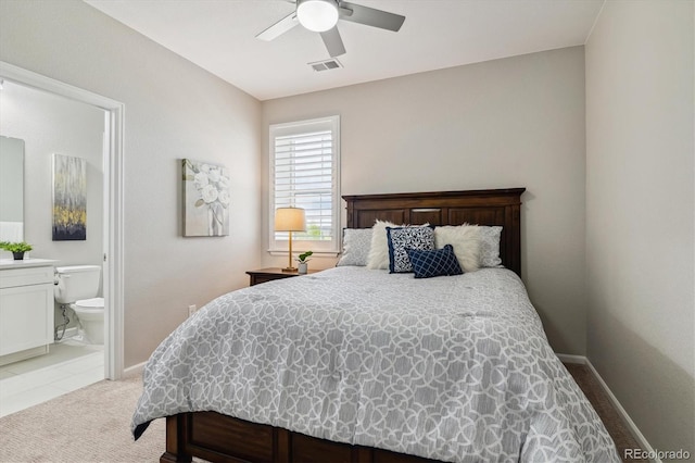 bedroom featuring visible vents, baseboards, light colored carpet, ensuite bath, and a ceiling fan