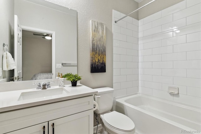 bathroom featuring tub / shower combination, toilet, vanity, and a textured wall