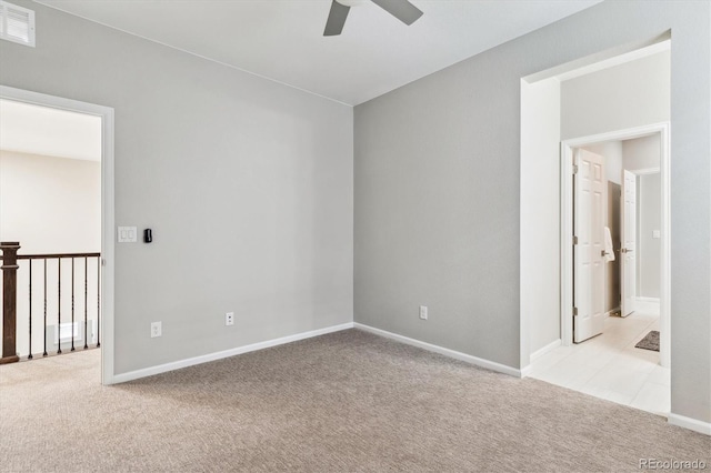 carpeted empty room with visible vents, baseboards, and a ceiling fan