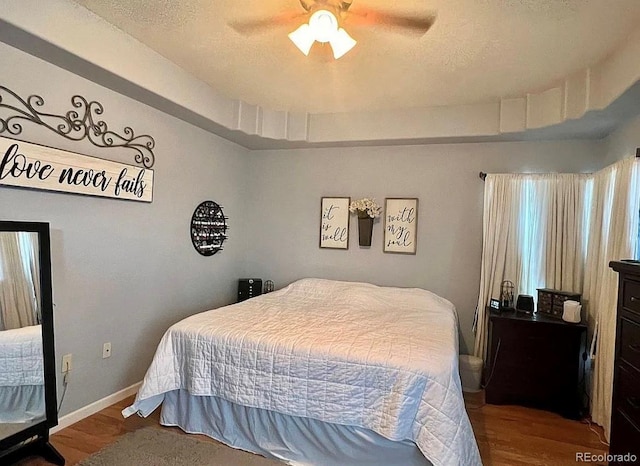 bedroom with a textured ceiling, hardwood / wood-style flooring, and ceiling fan