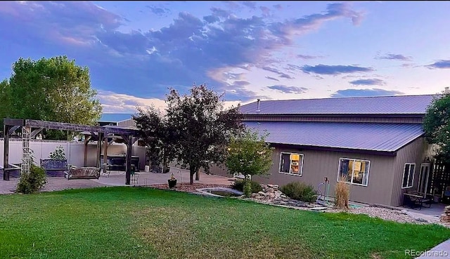 back house at dusk with a yard, a pergola, and a patio